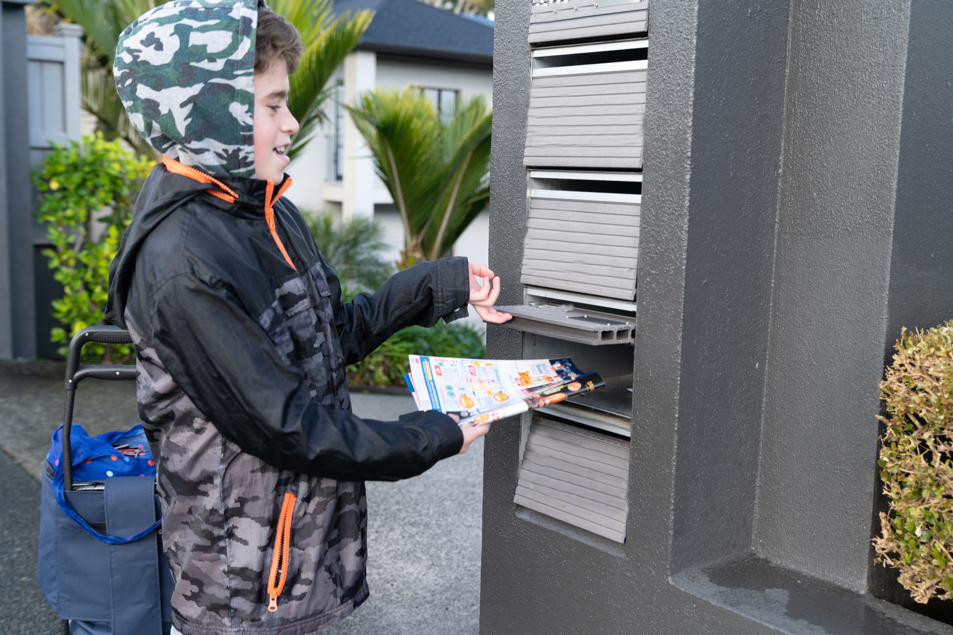 Young boy earning a small income by delivering advertising brochures to private letterboxes in residential suburb